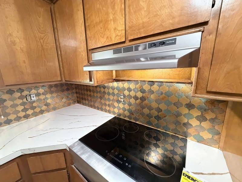 New cooktop and range hood with tile backsplash