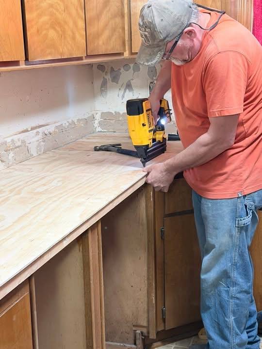Volunteer installing new countertop with a nail gun
